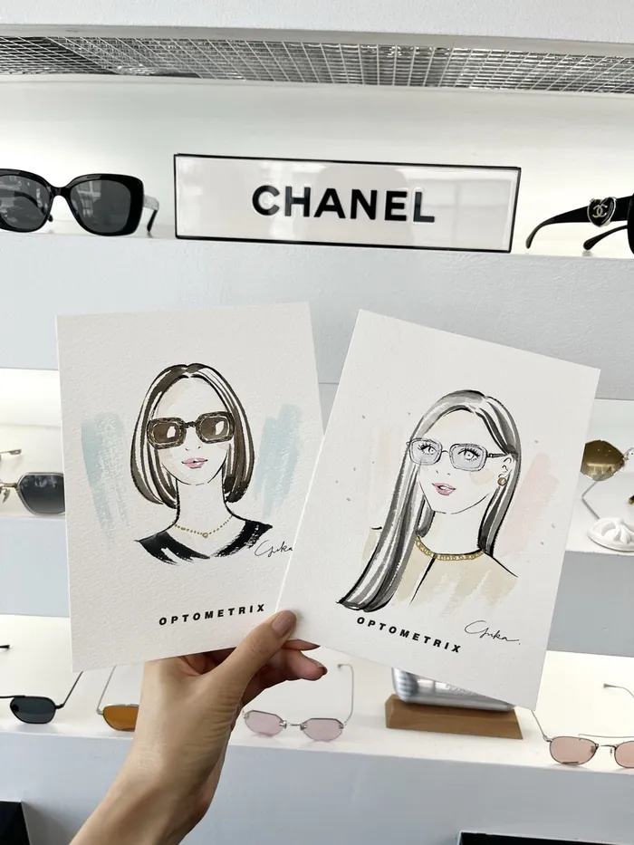 Hand holding illustrations of women wearing glasses in optical store