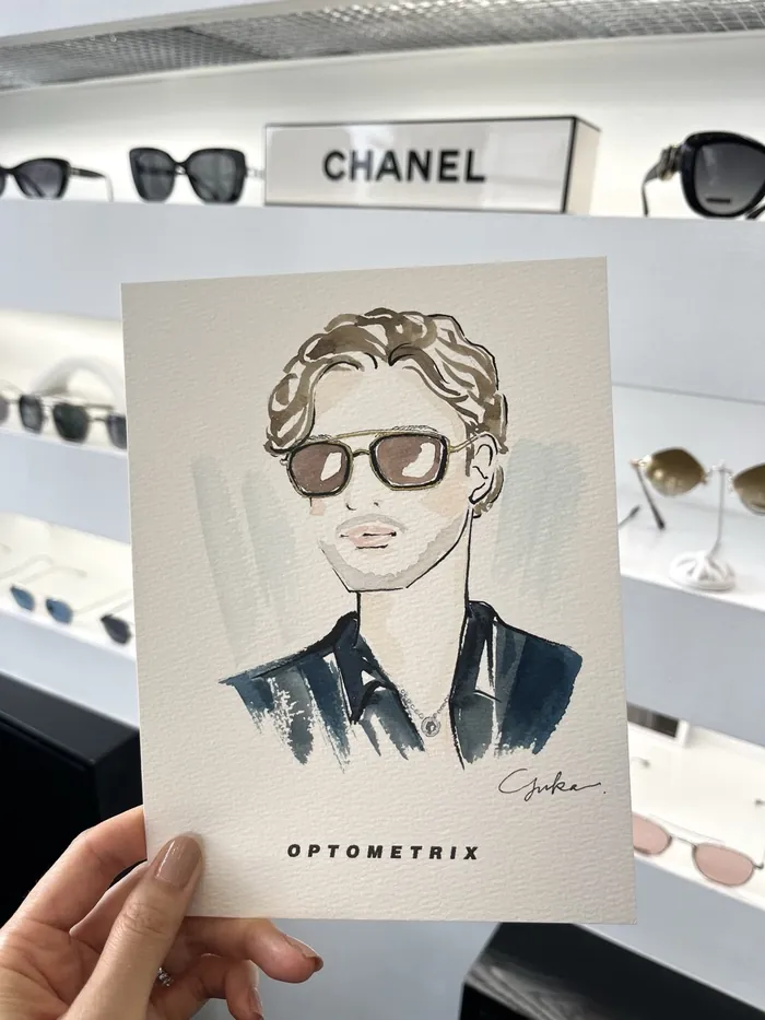 Hand holding illustrated portrait of man with sunglasses in eyewear store