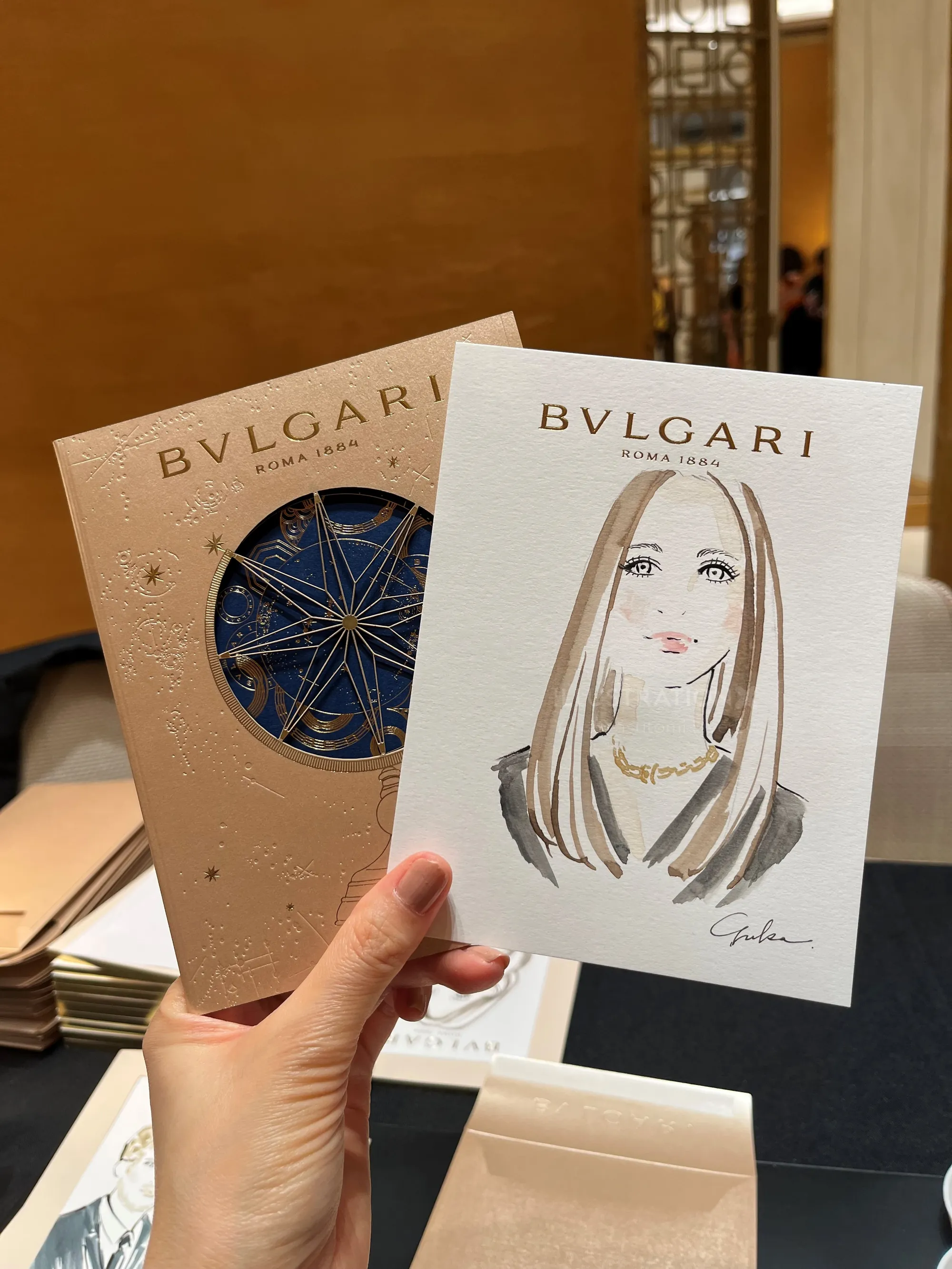 Hand holding Bvlgari invitation and illustrated portrait by Yuka Yasutomi