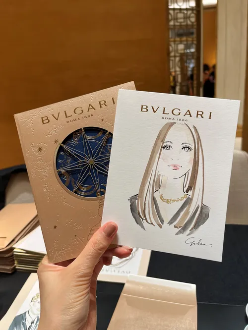 Hand holding Bvlgari invitation and illustrated portrait by Yuka Yasutomi
