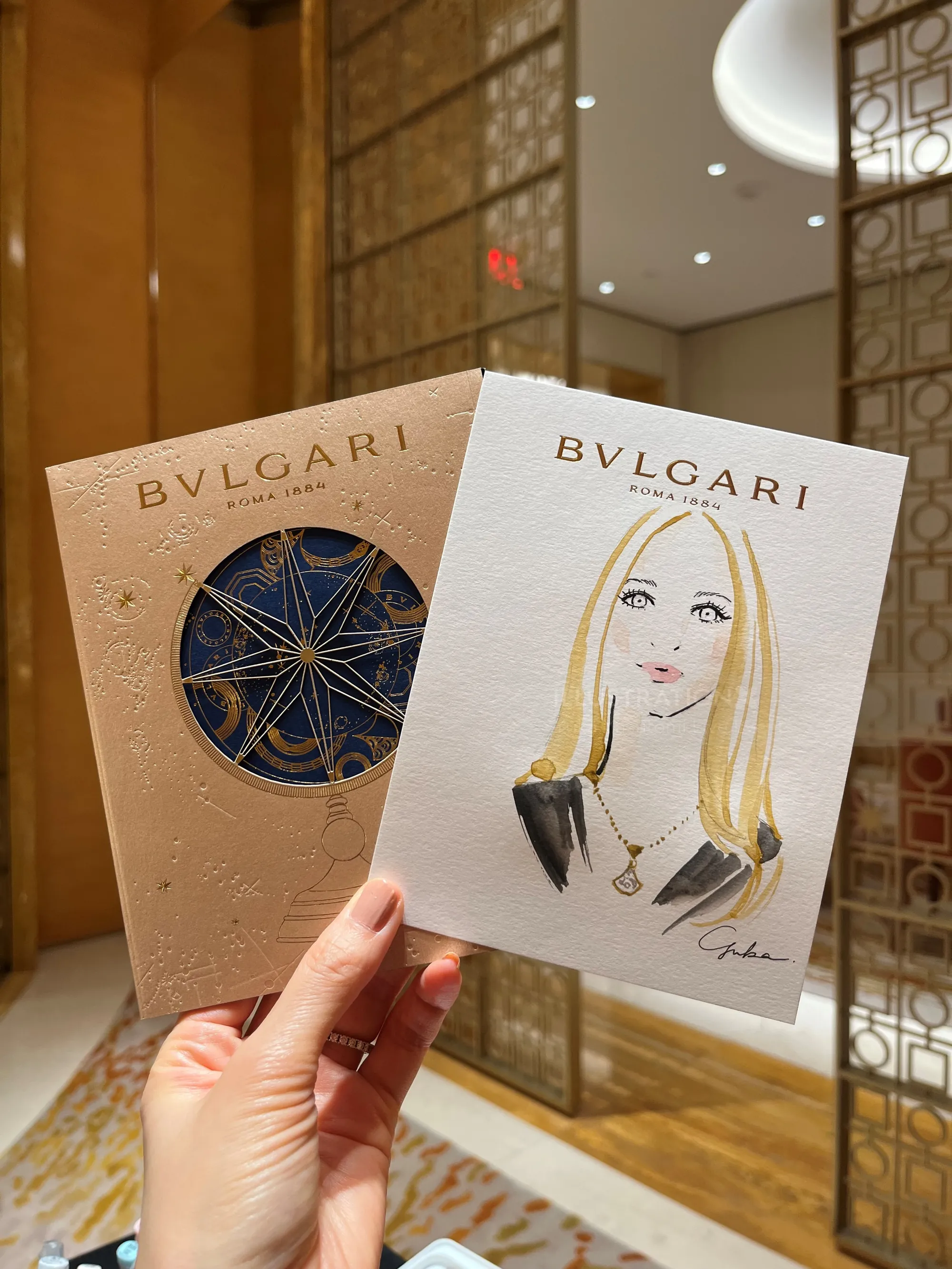 Hand holding Bvlgari invitation cards including fashionable woman illustration by Yuka Yasutomi
