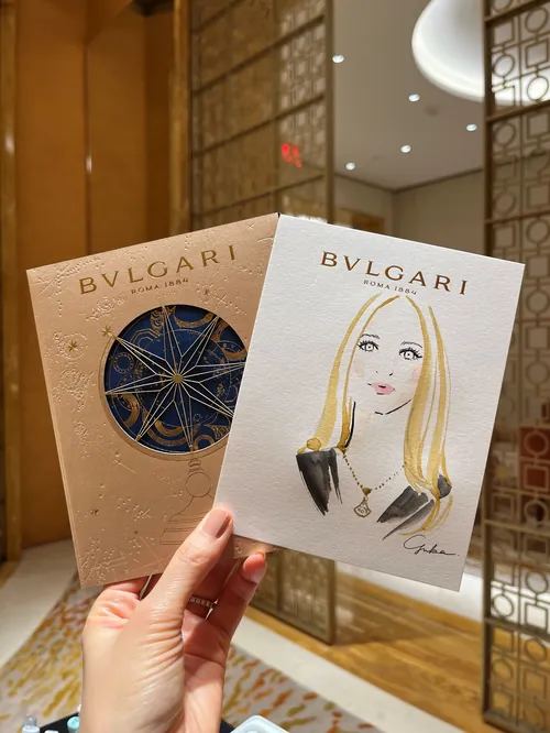 Hand holding Bvlgari invitation cards including fashionable woman illustration by Yuka Yasutomi