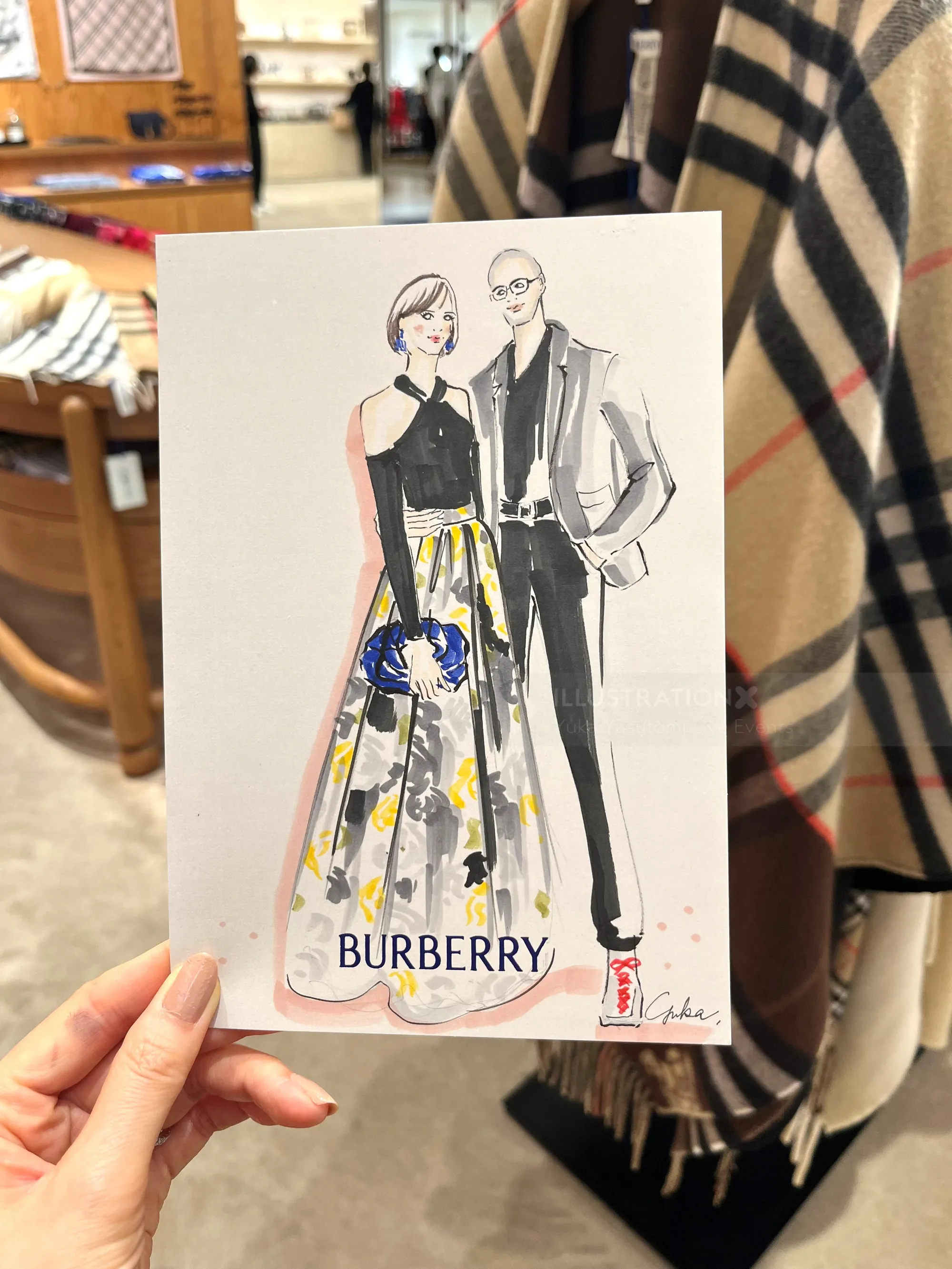 Fashion illustration of a man and woman wearing Burberry outfits by Yuka Yasutomi