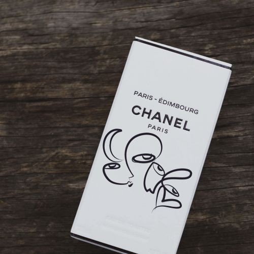CHANEL Paris product box with minimalist black line art on wood background