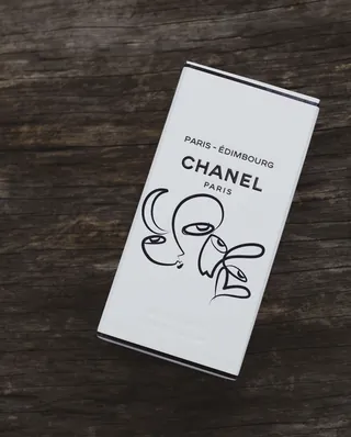 CHANEL Paris product box with minimalist black line art on wood background