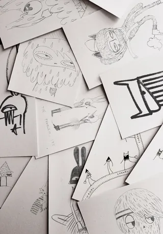 Black and white sketches of characters and objects on scattered papers