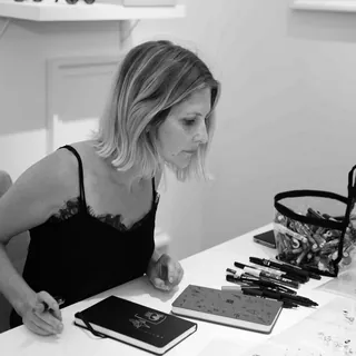 Woman focused on drawing with pens and sketchbook on desk
