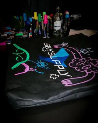 Black fabric decorated with colorful neon graffiti drawings and markers