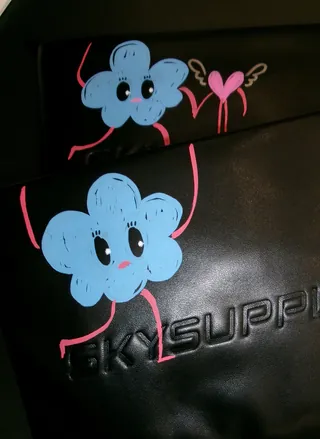 Blue flower cartoon holding a pink heart with wings on black surface