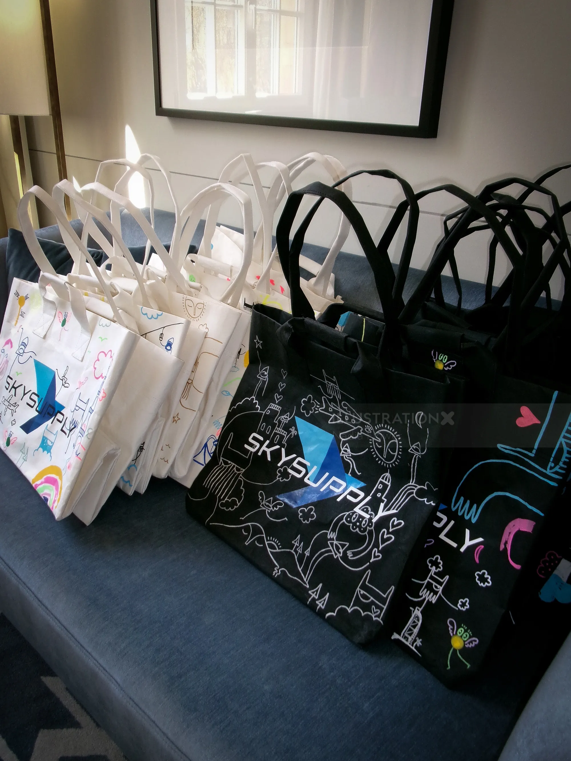 Rows of white and black reusable tote bags with colorful abstract patterns