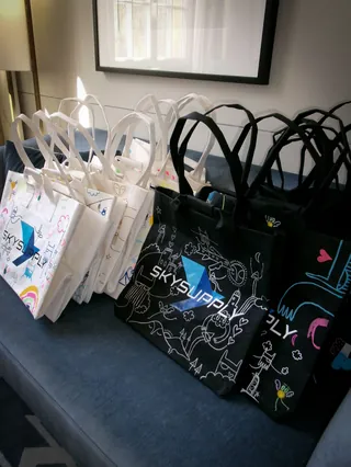 Rows of white and black reusable tote bags with colorful abstract patterns