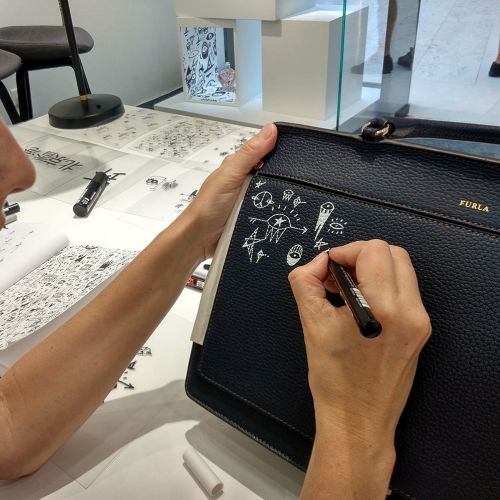 Hand drawing white doodles on black leather purse with pen