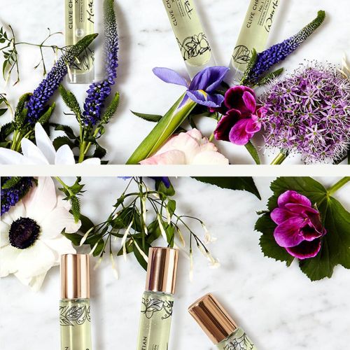 Three perfume bottles with flowers and grapefruit on white surface