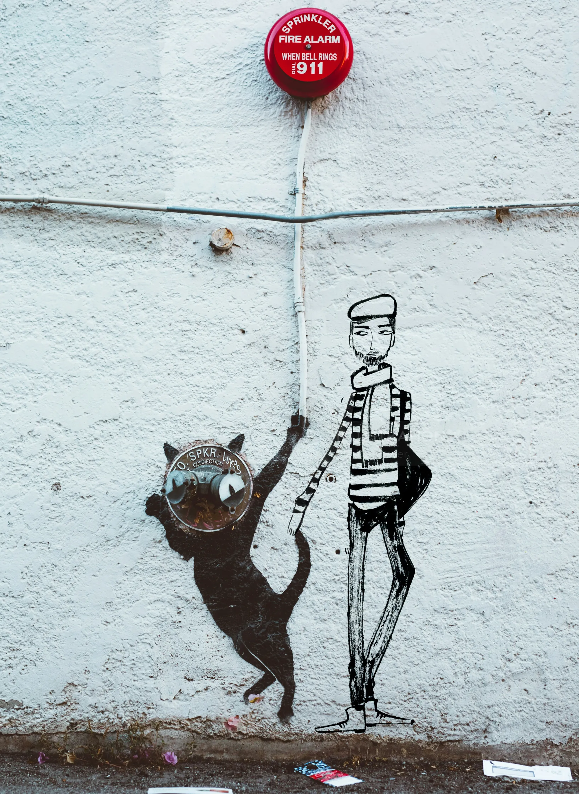 Street art of a cat and a striped human figure on a wall by Nadia Flower