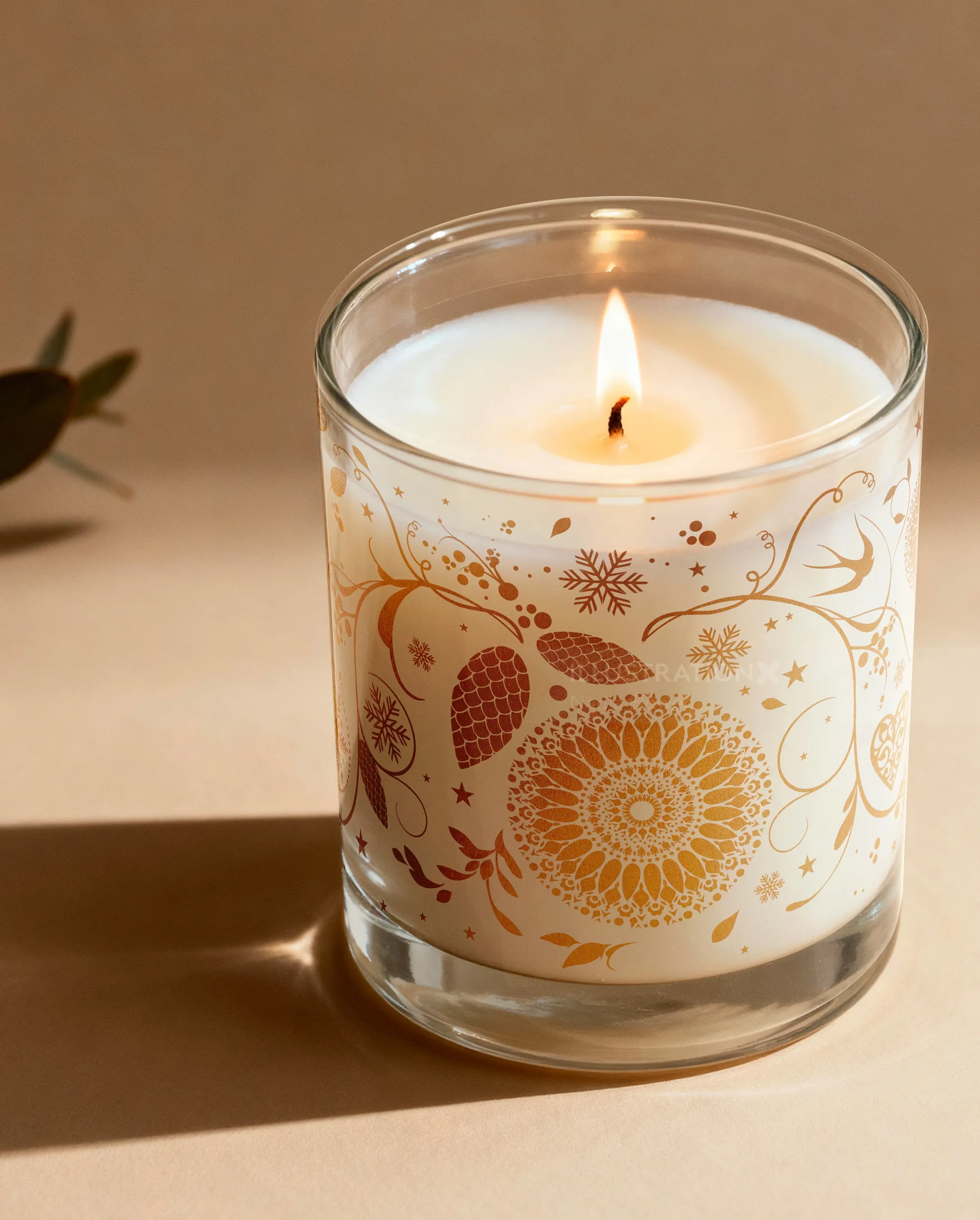 Lit scented candle in glass with gold floral design by Nadia Flower
