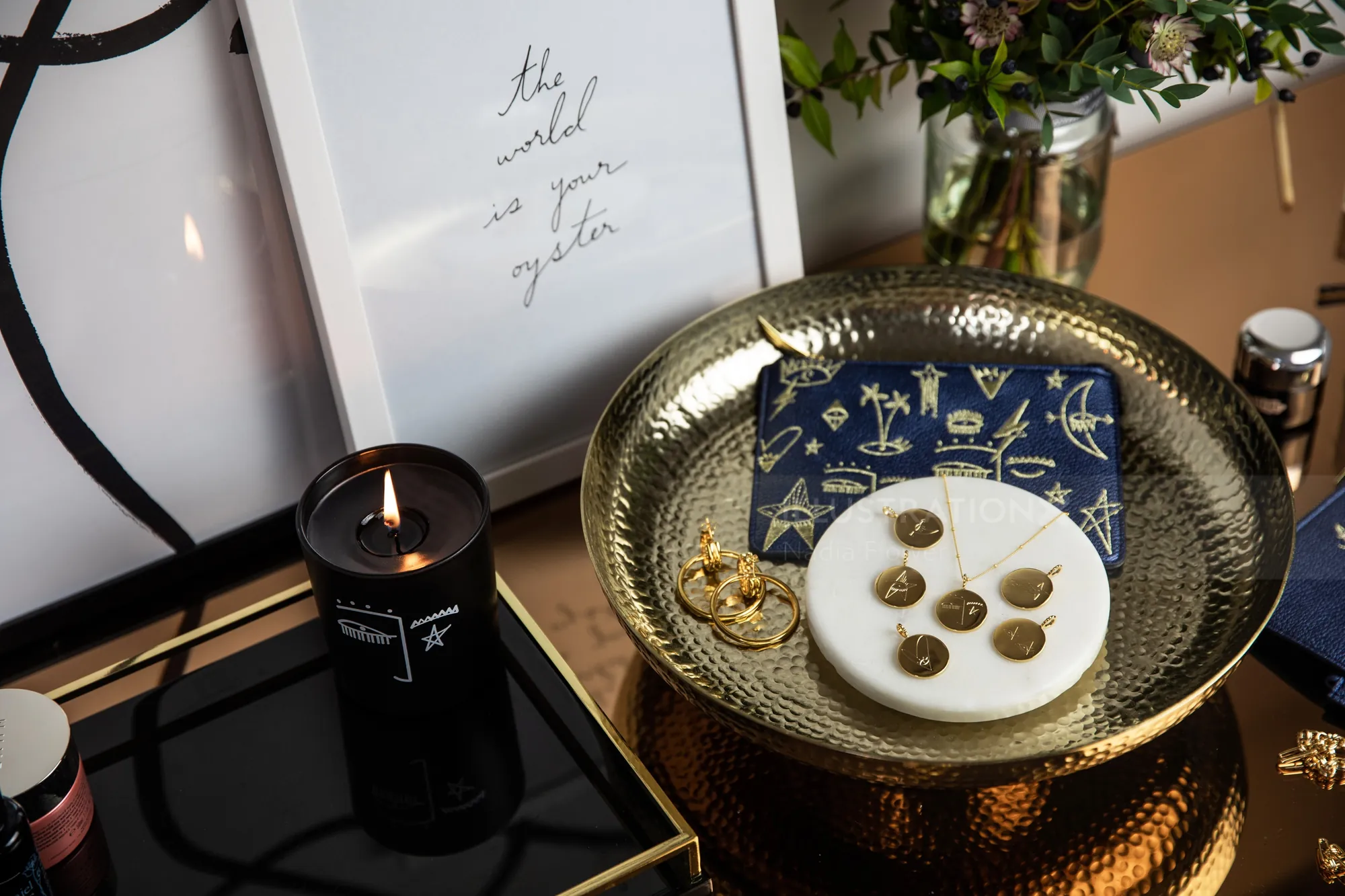 Gold tray with jewelry, star card, and lit candle by Nadia Flower