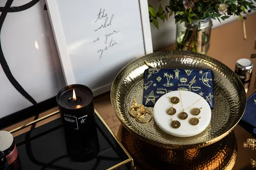 Gold tray with jewelry, star card, and lit candle by Nadia Flower