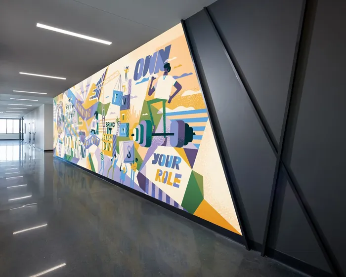 Geometric mural with motivational text 'Own Your Role' in hallway