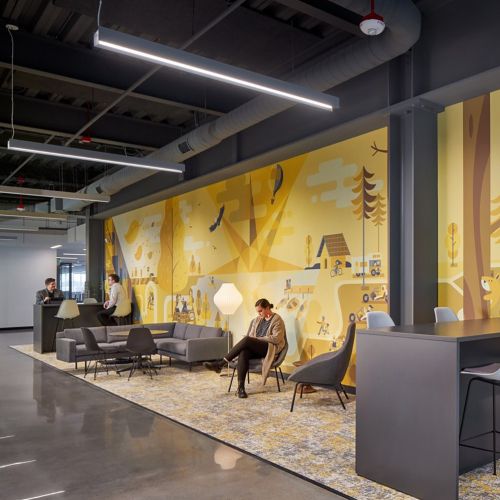 Office lounge with yellow mural, gray chairs, and bar stools